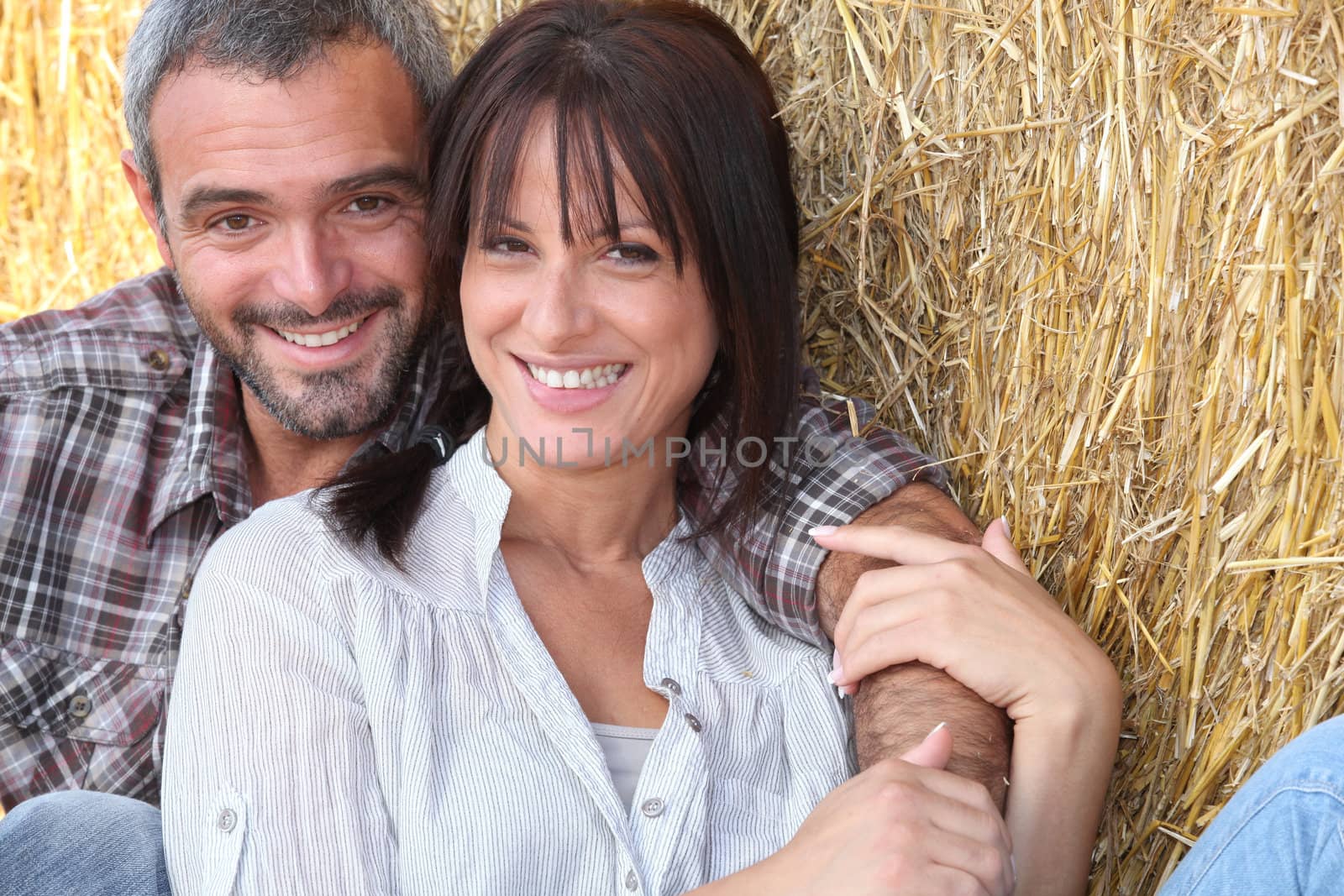 Farming couple sitting in the hay by phovoir