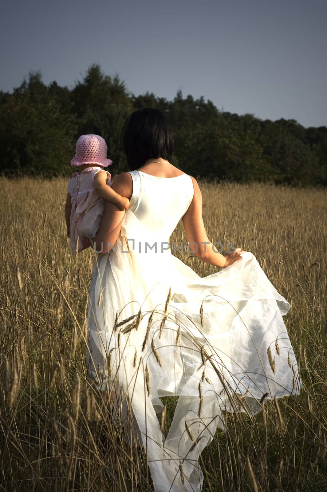 Women with her baby is walking  threw the field of  rye.