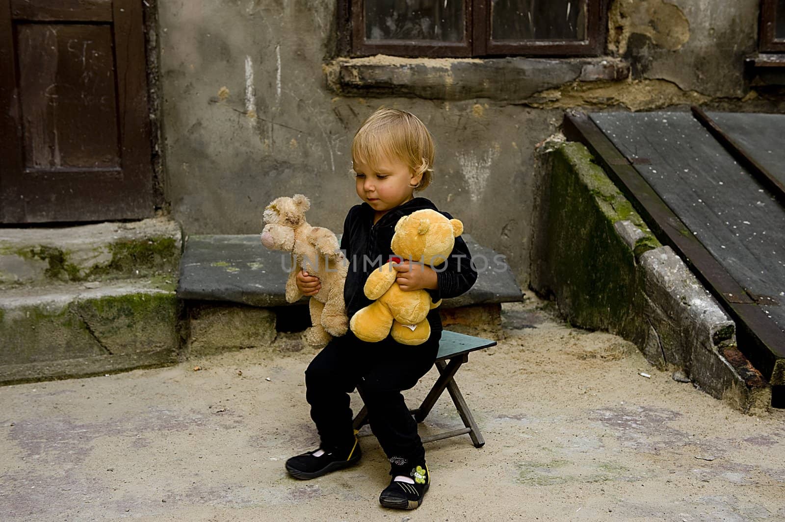 beautifull baby is sitting on the chair ,and holding teddy bear