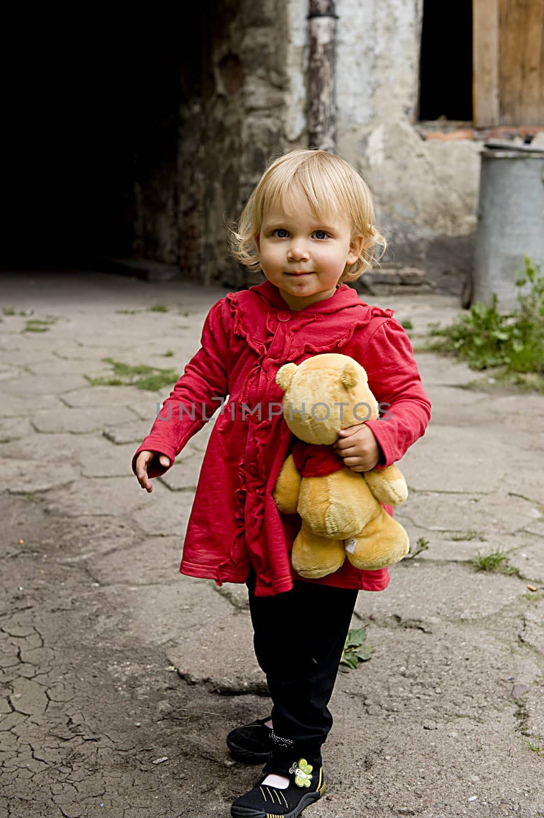 little girl holding teddy bear in the open air