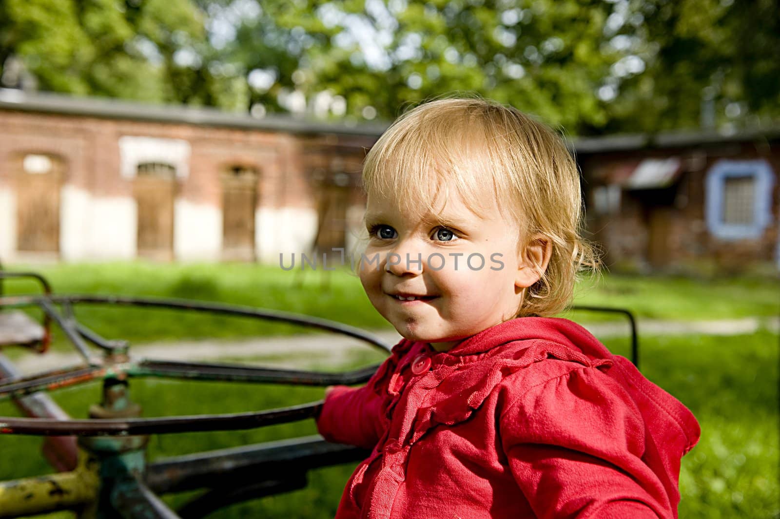 little girl is sitting on the merry-go-round