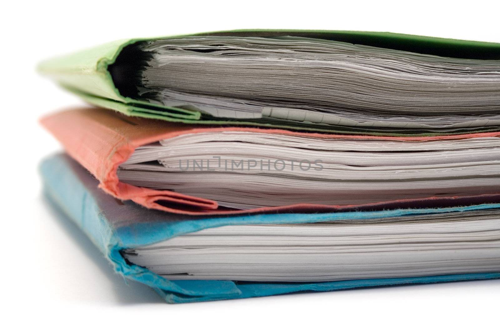 Colorful stacked binders full of documents. Isolated on a white background.