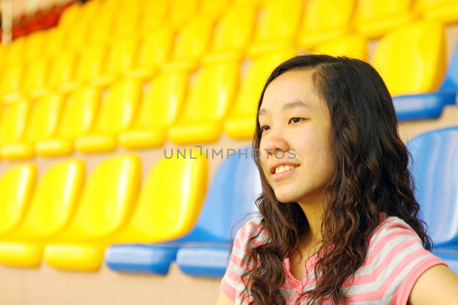 Asian girl on stadium, she is watching matches on court. 