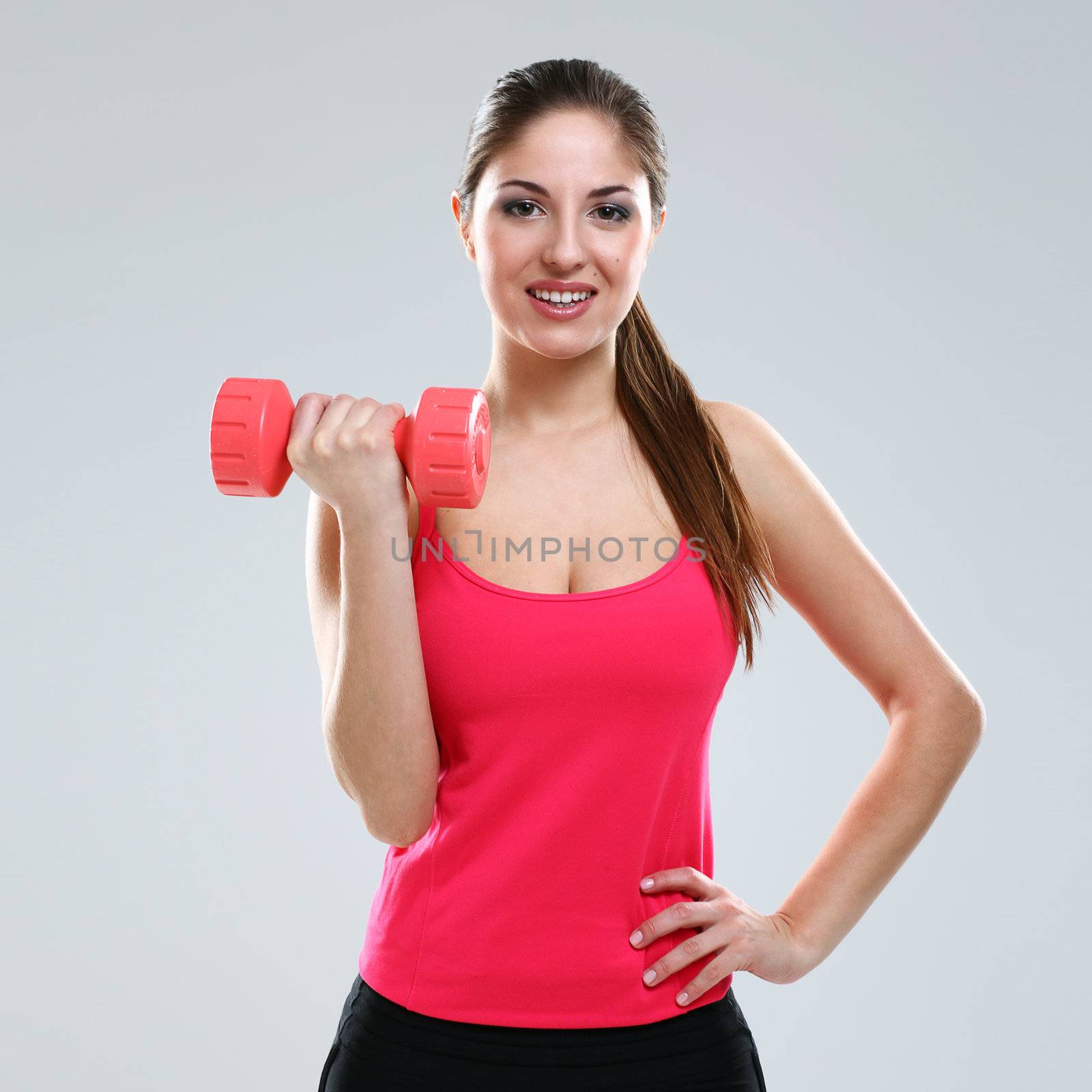 Young beautiful woman in fitness wear with dumbbells isolated over background