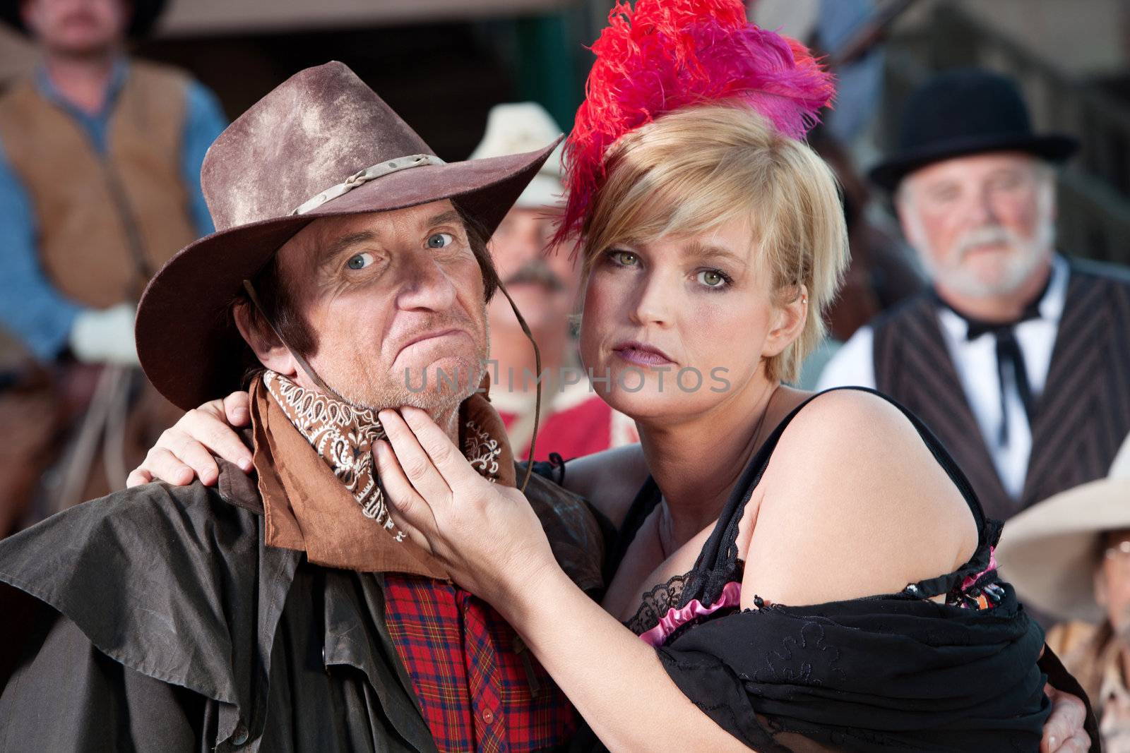 A mean looking cowboy is caressed by the local bargirl.