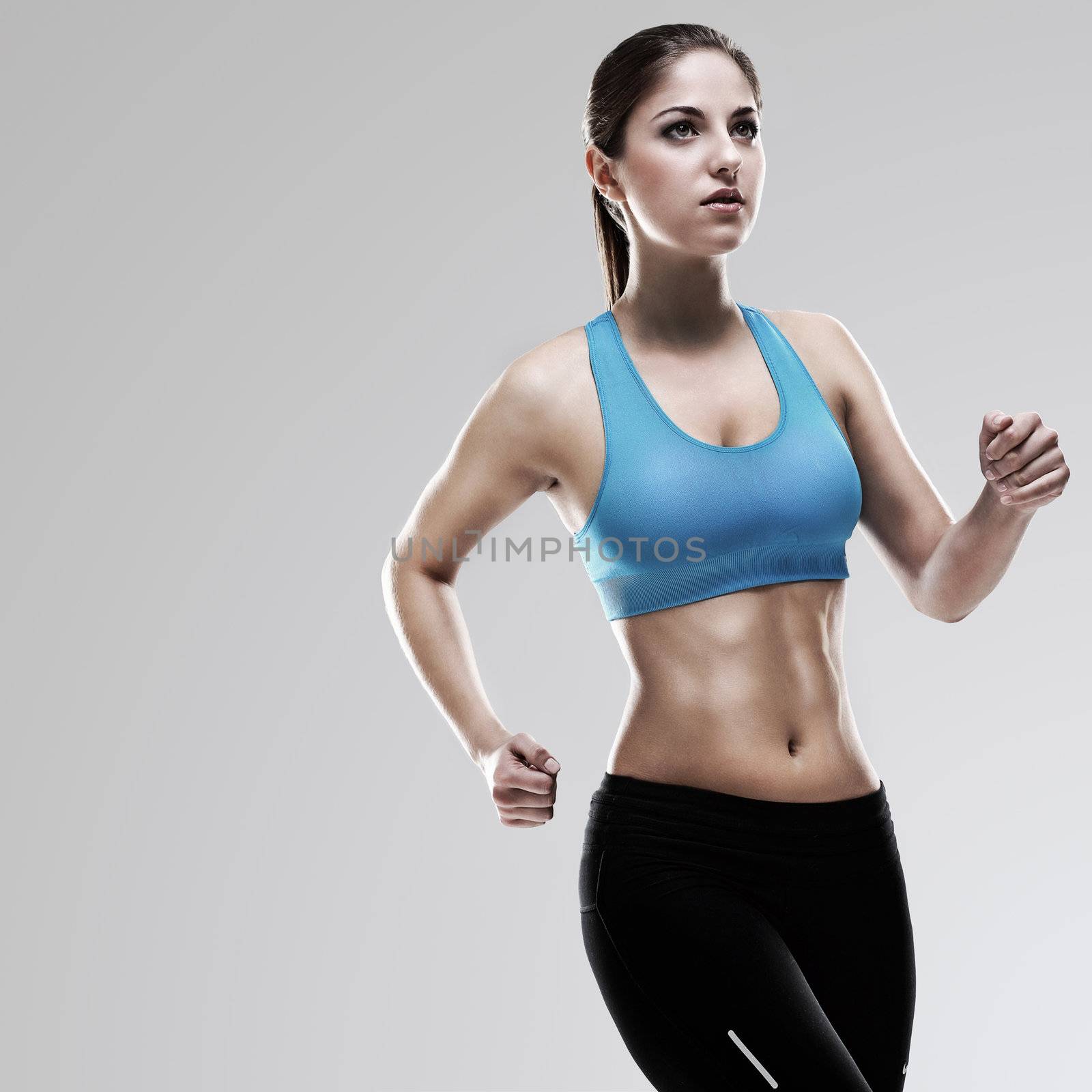 Young beautiful woman in fitness wear runs isolated over background