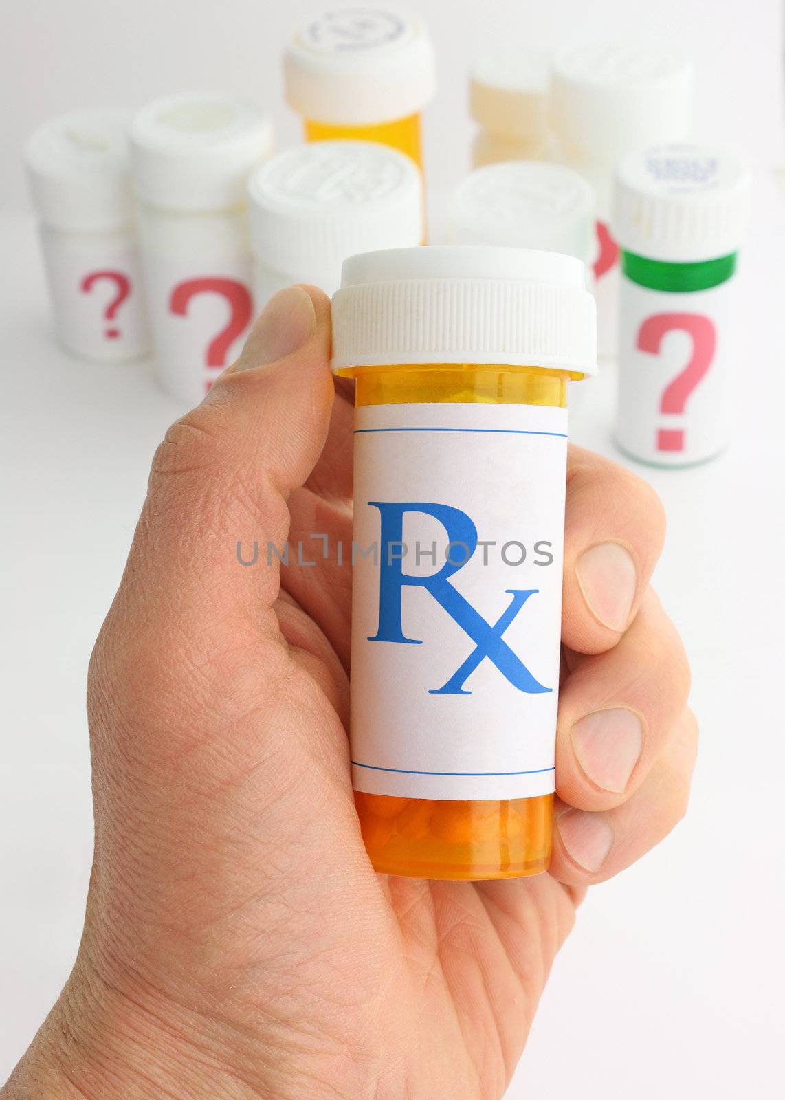 A hand holding a medicine bottle marked with an Rx pharmacy mark. A variety of pill bottles labeled with large question marks are in the background.