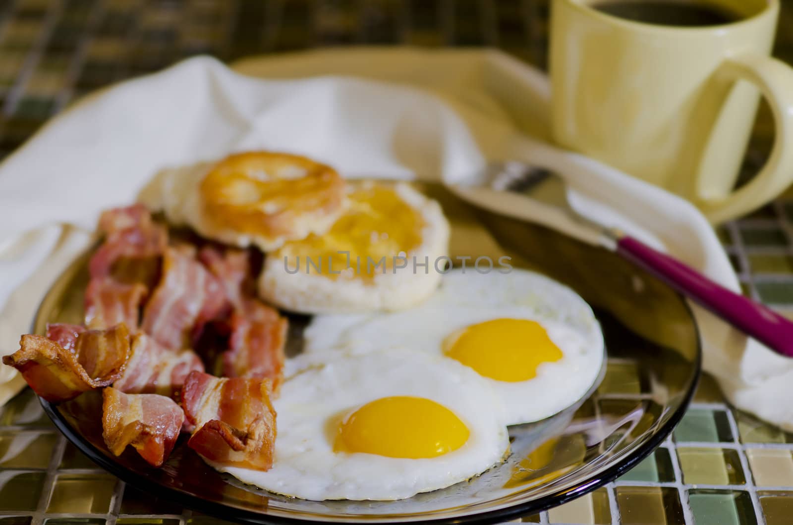 Breakfast plate  with eggs, bacon, coffee, and biscuits with apple jelly.