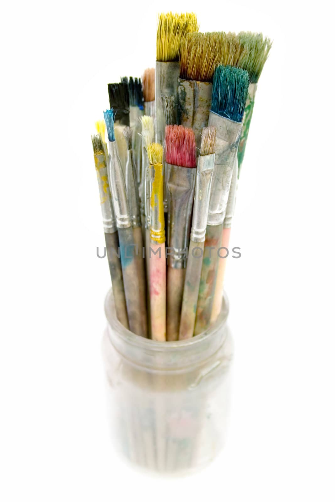 Bunch of dirty paintbrushes in a glass. Isolated on a white background.