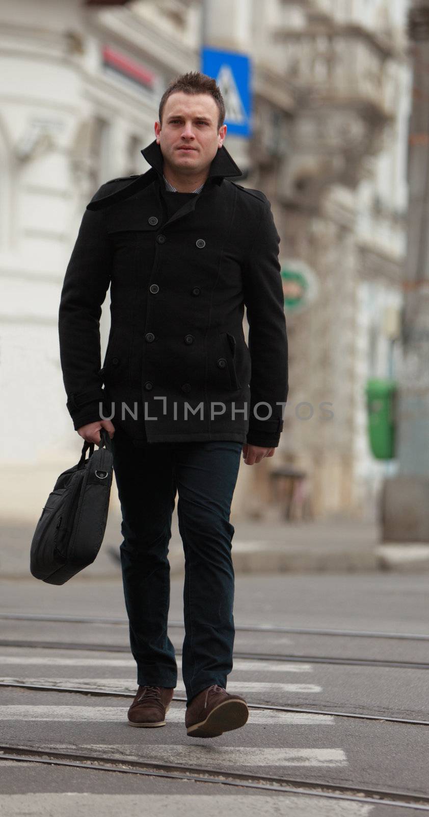 Businessman crossing the street in an old European city.