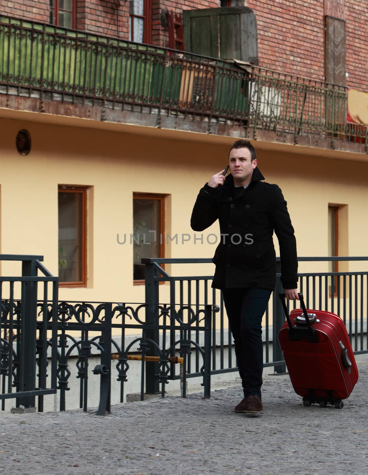 Young businessman on the phone waling in a small cobbled street in a city.