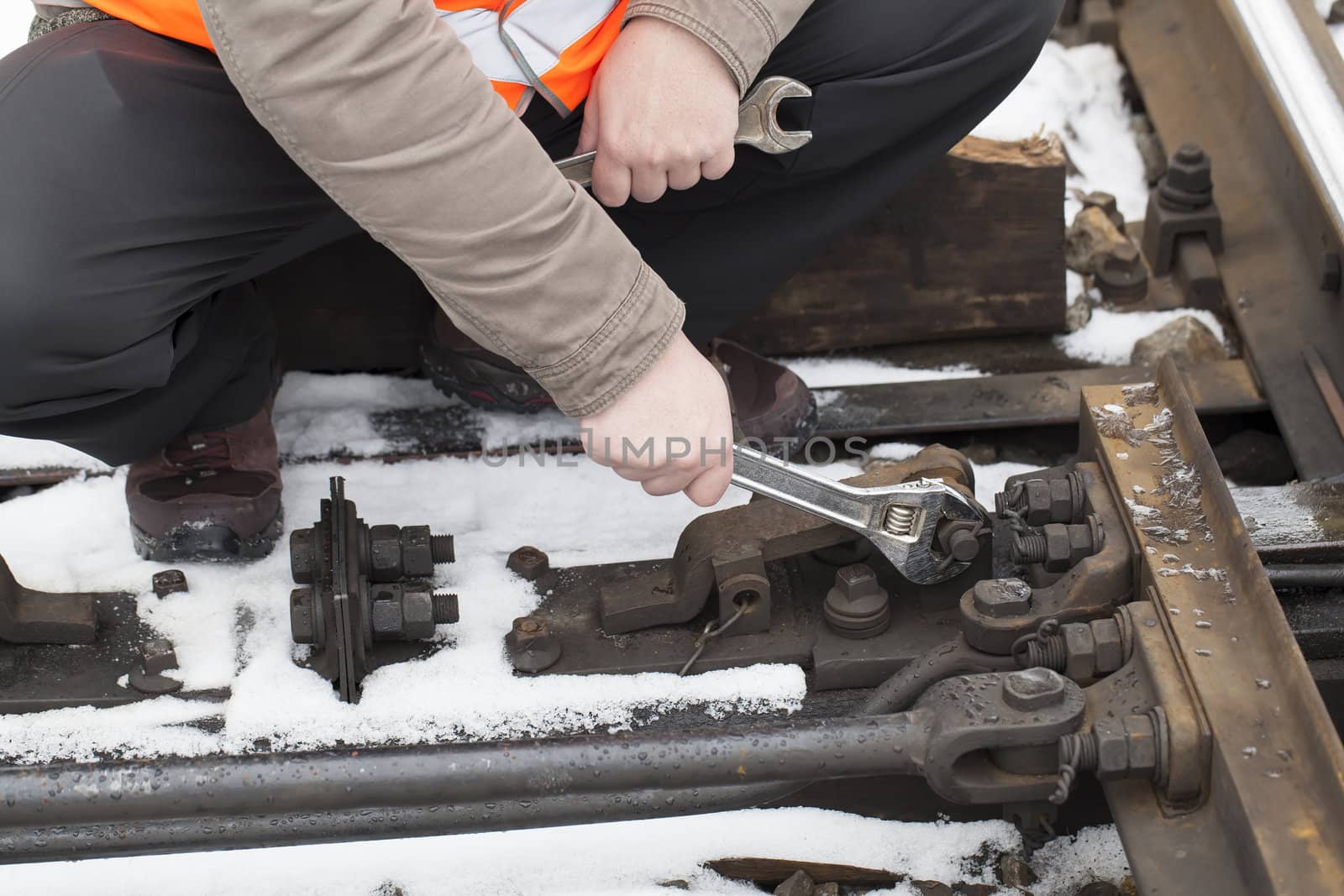 Man's hand with adjustable wrench at the railroad by A.L.