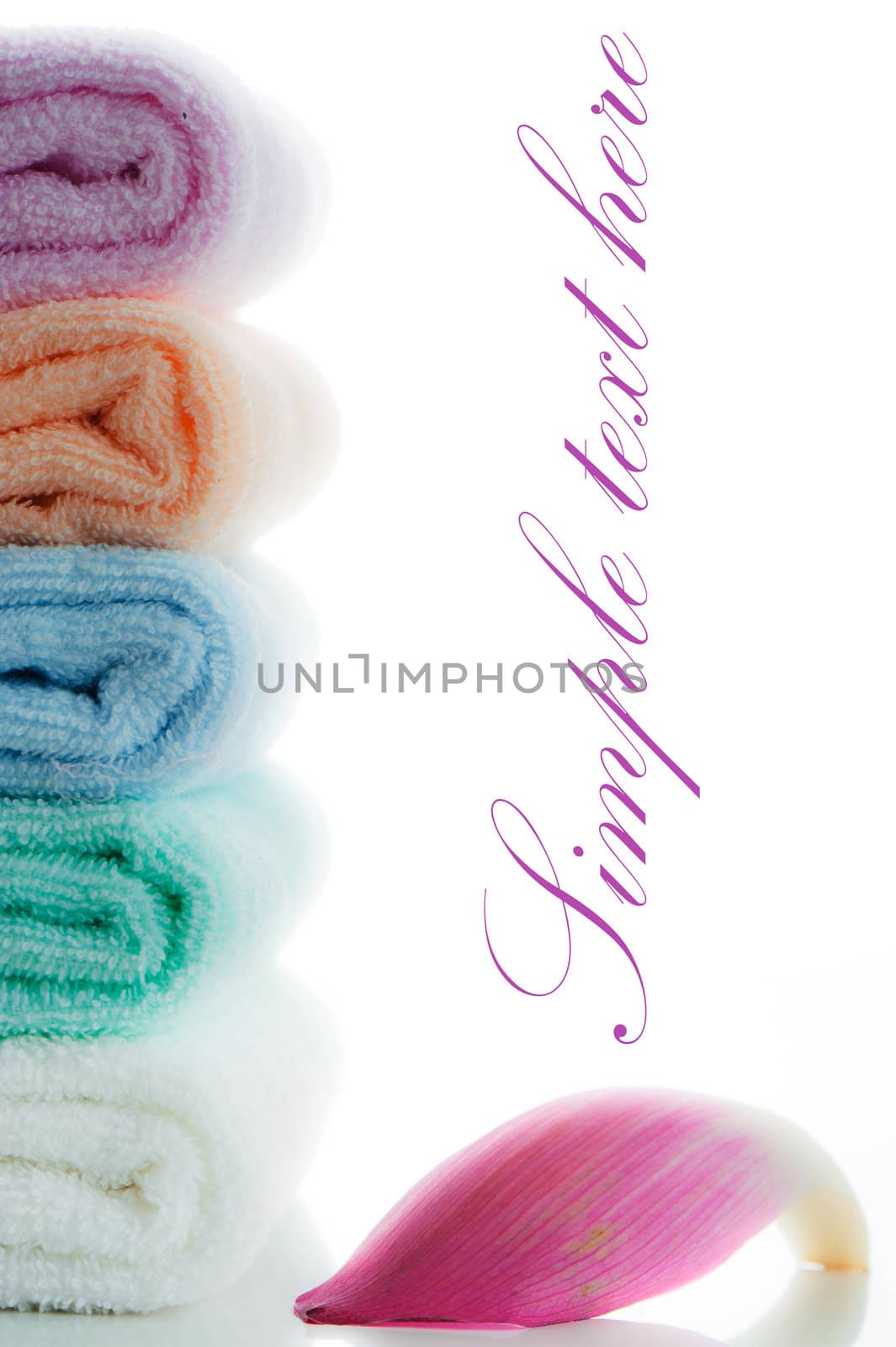 multicolor towels stacked with a lotus petal on white background and area for your text
