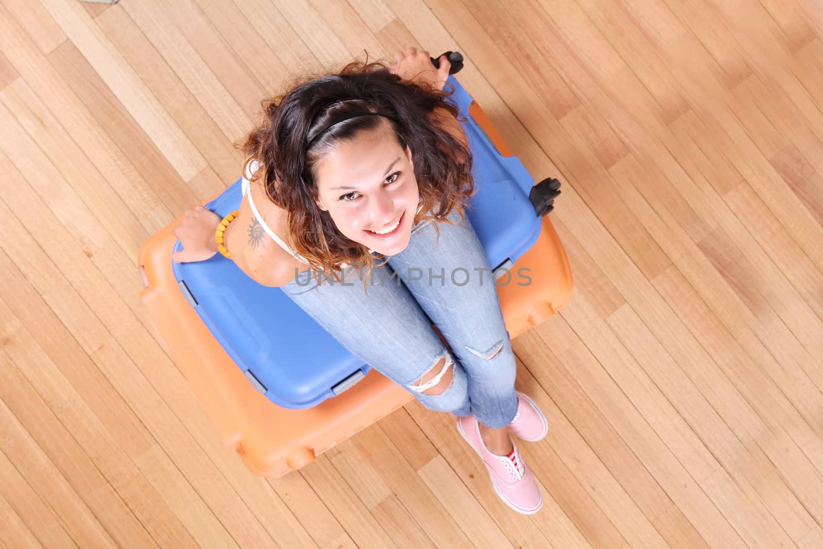 A young woman sitting on a stack of suitcases.