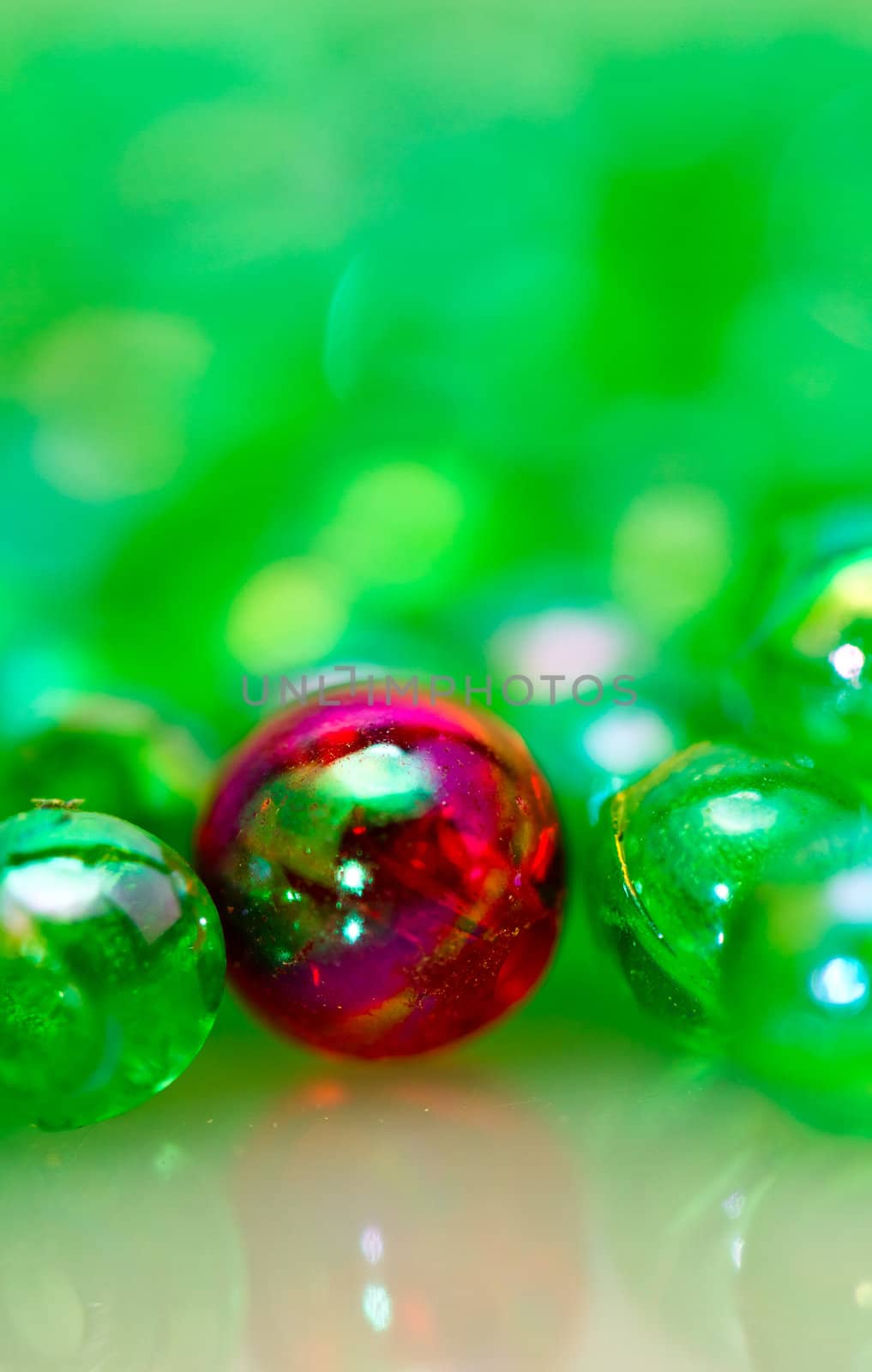Red beads among the green smaller beads with mirror image in portrait orientation