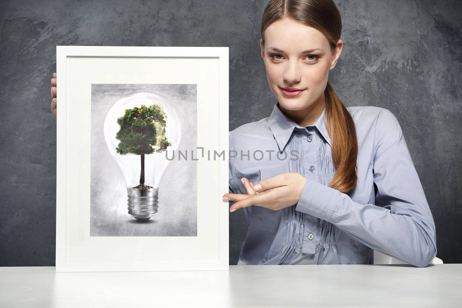 Girl holds a frame with the image of Eco concept, green tree growing in a bulb