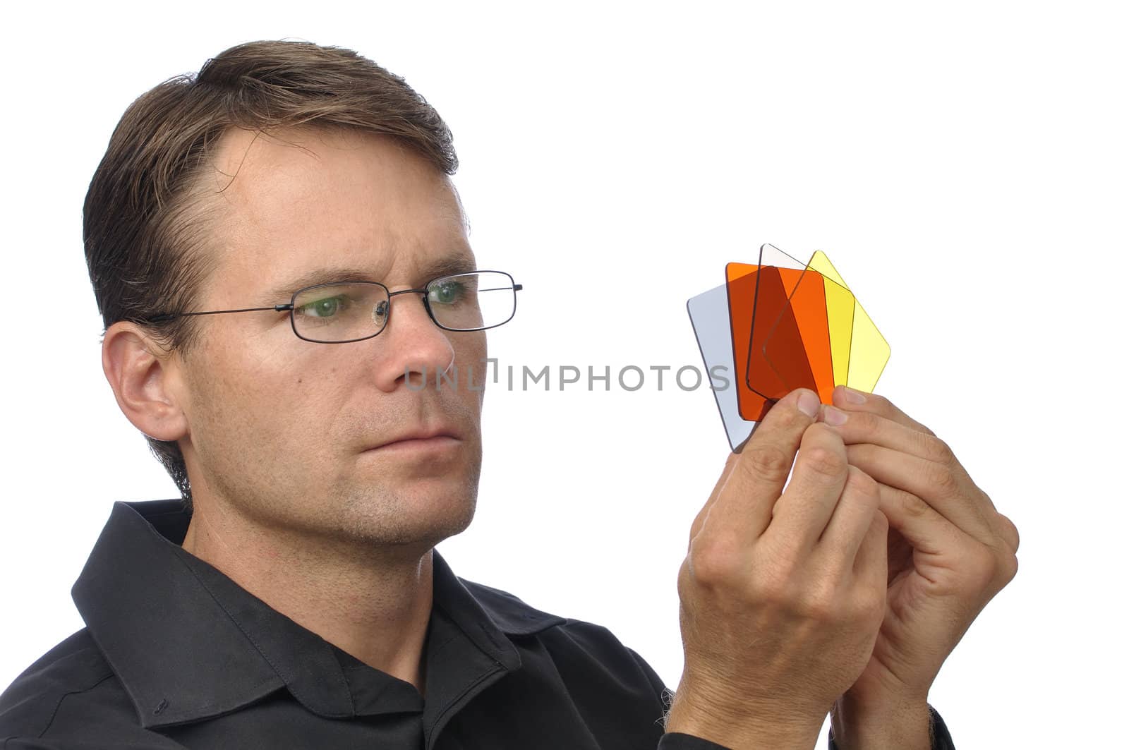 Handsome male photographer holds and inspects colored square filters on white background