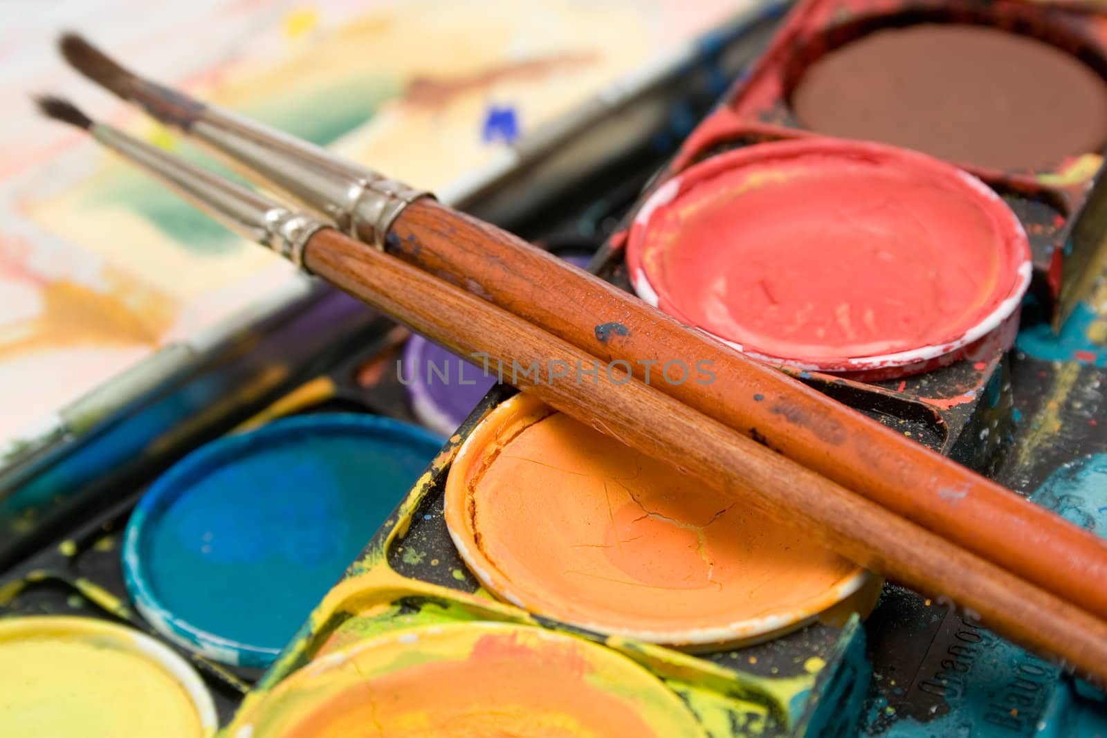 Detail shot on a box of watercolors and two paintbrushes.