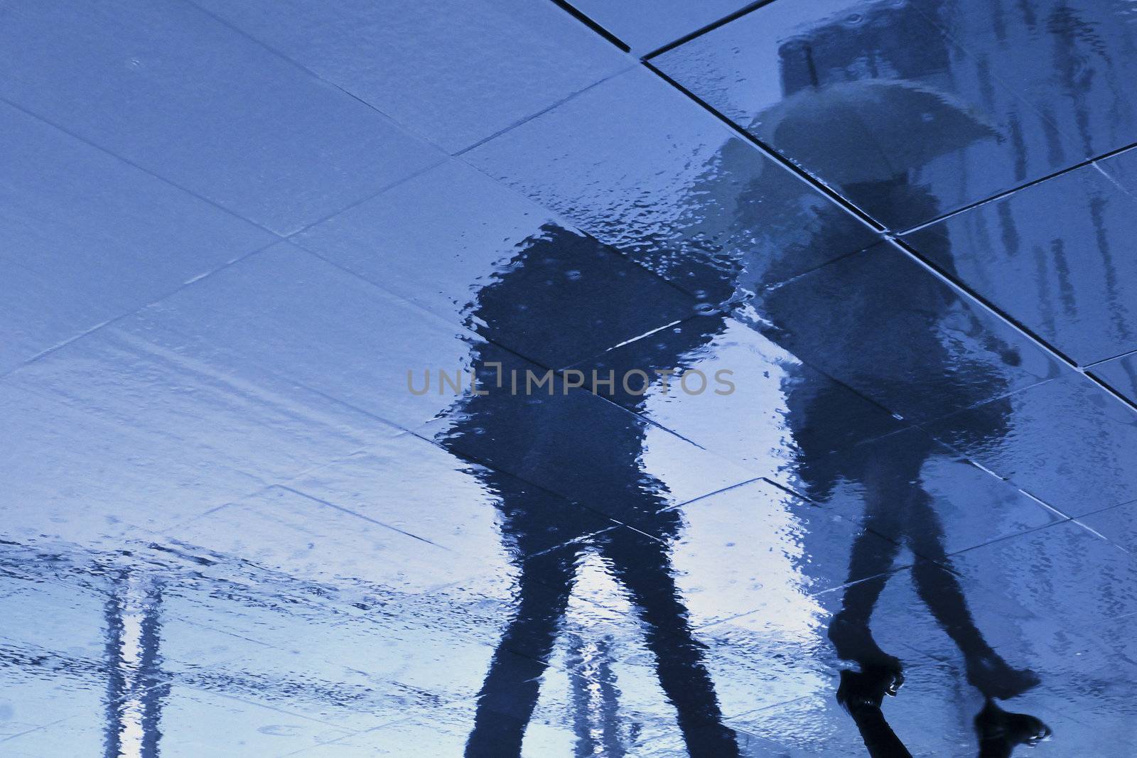 rainy pavement reflection of walking couple in Tokyo, Japan during rainy season which usually takes time in June