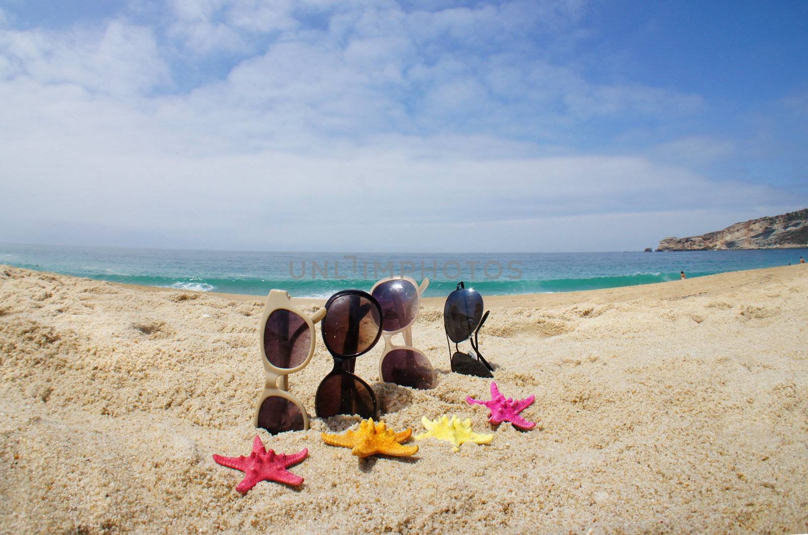 Holiday with friends � four pair of sunglasses on the beach and multi color sea stars