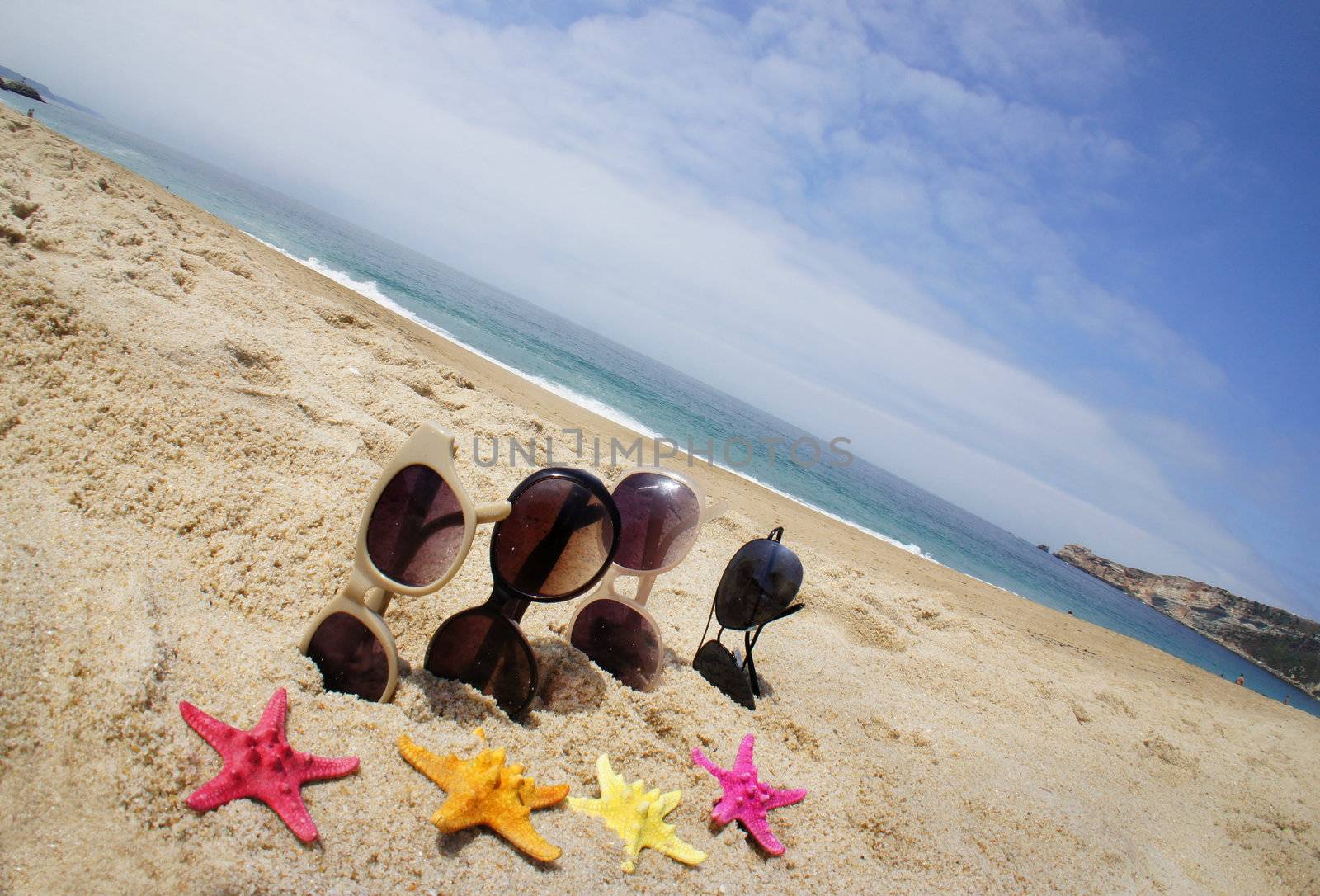 Holiday with friends � four pair of sunglasses on the beach and multicolor sea stars