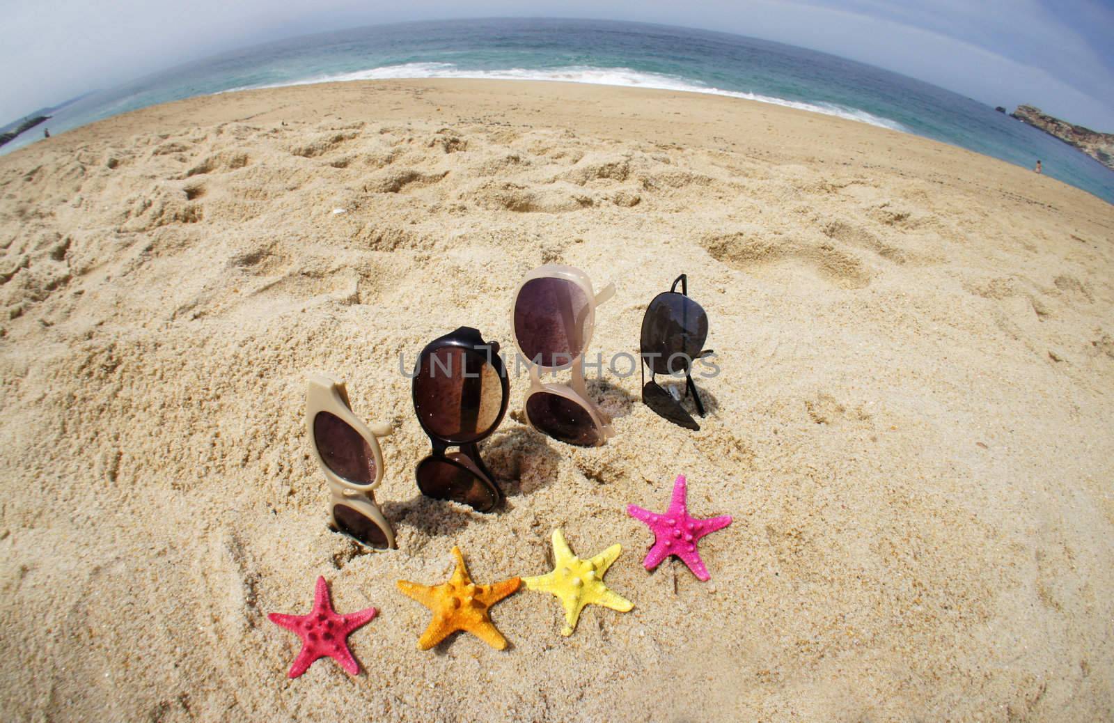 Holiday with friends � four pair of sunglasses on the beach and multi color sea stars
	