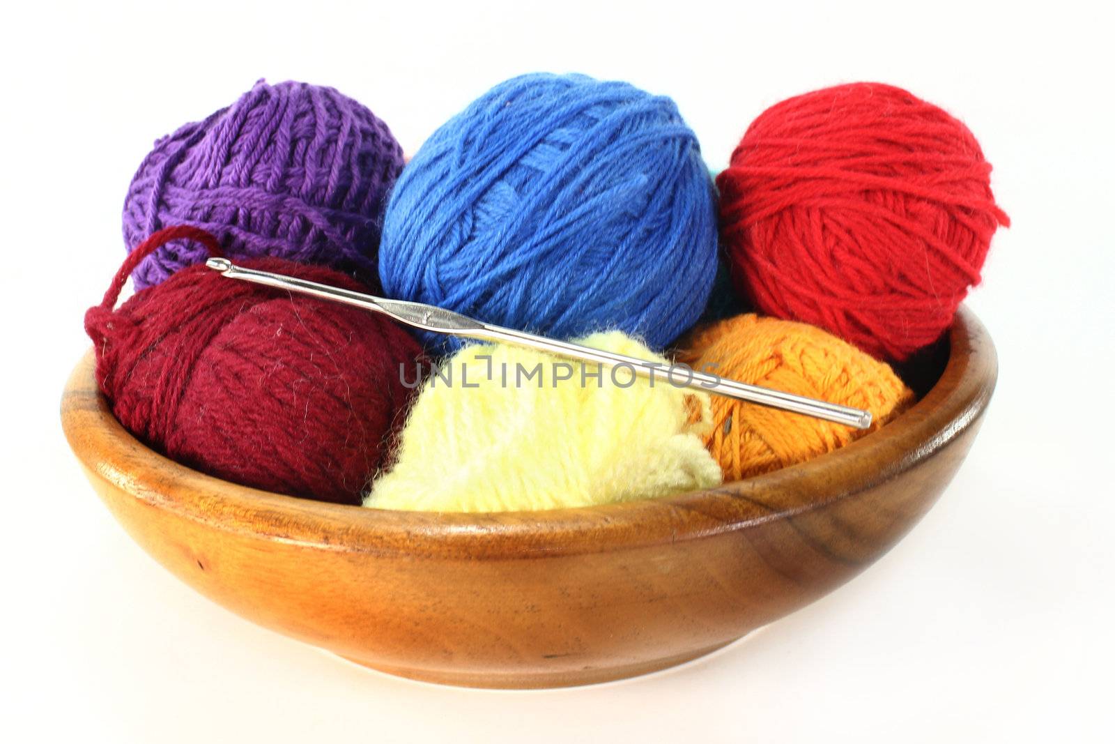 colorful balls of wool with crochet hook on a white background
