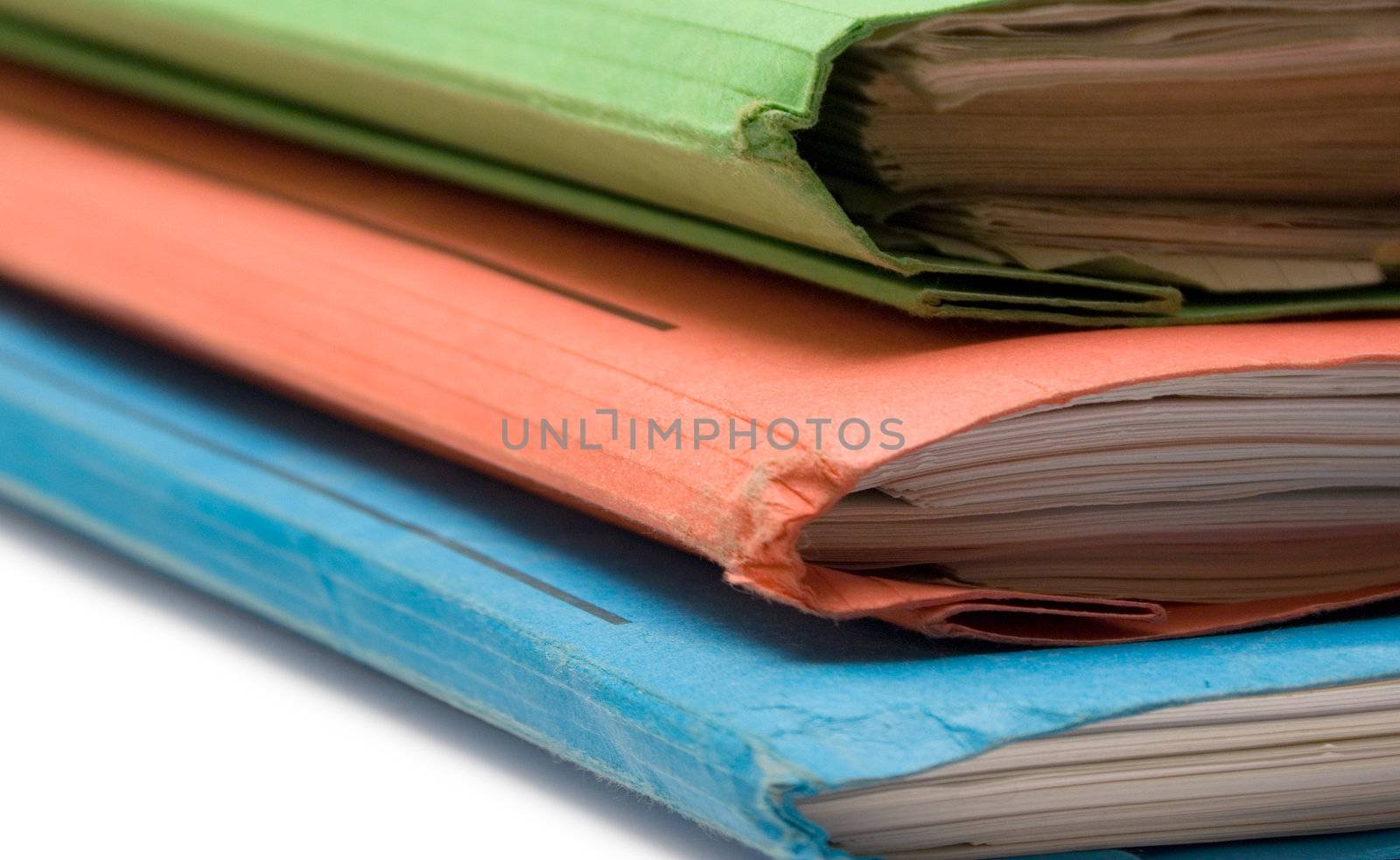 Stack of colorful binders full of documents.