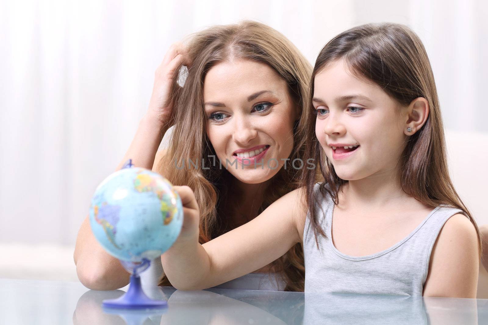 Mother and daughter looking at a globe by robert_przybysz