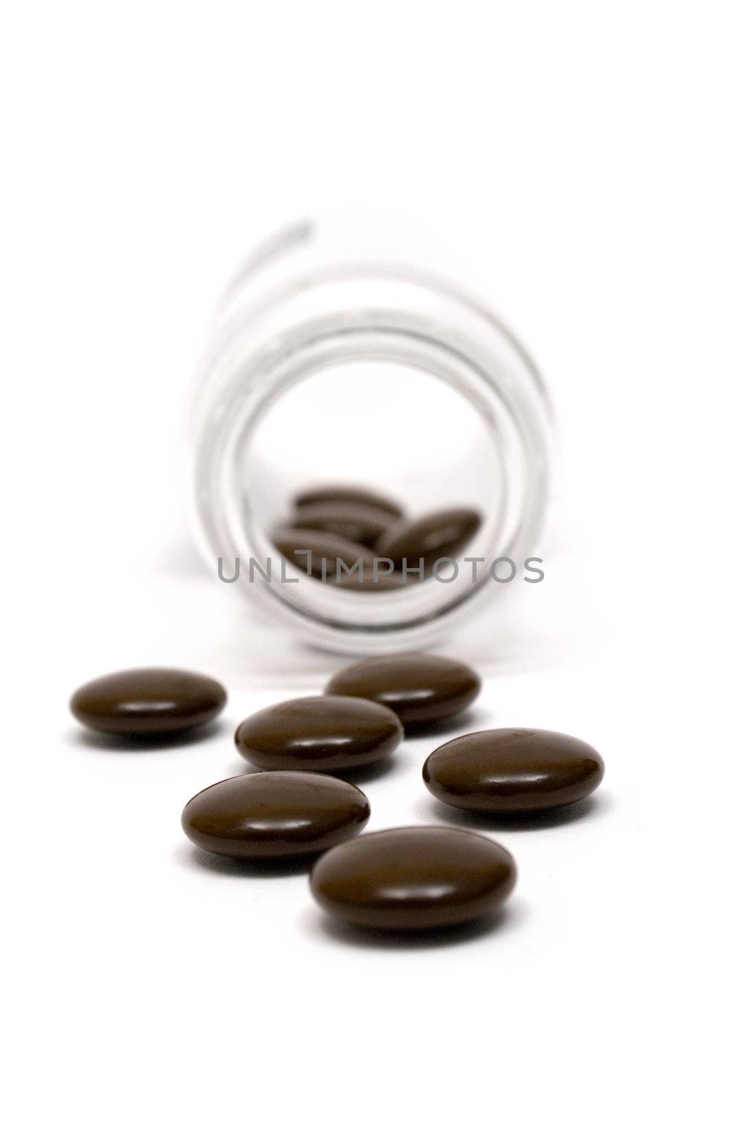 Glass bottle and brown pills isolated on a white background.