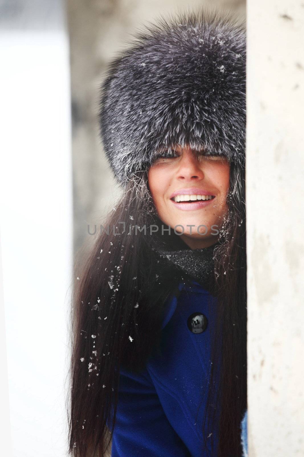  woman in fur hat hide behind column