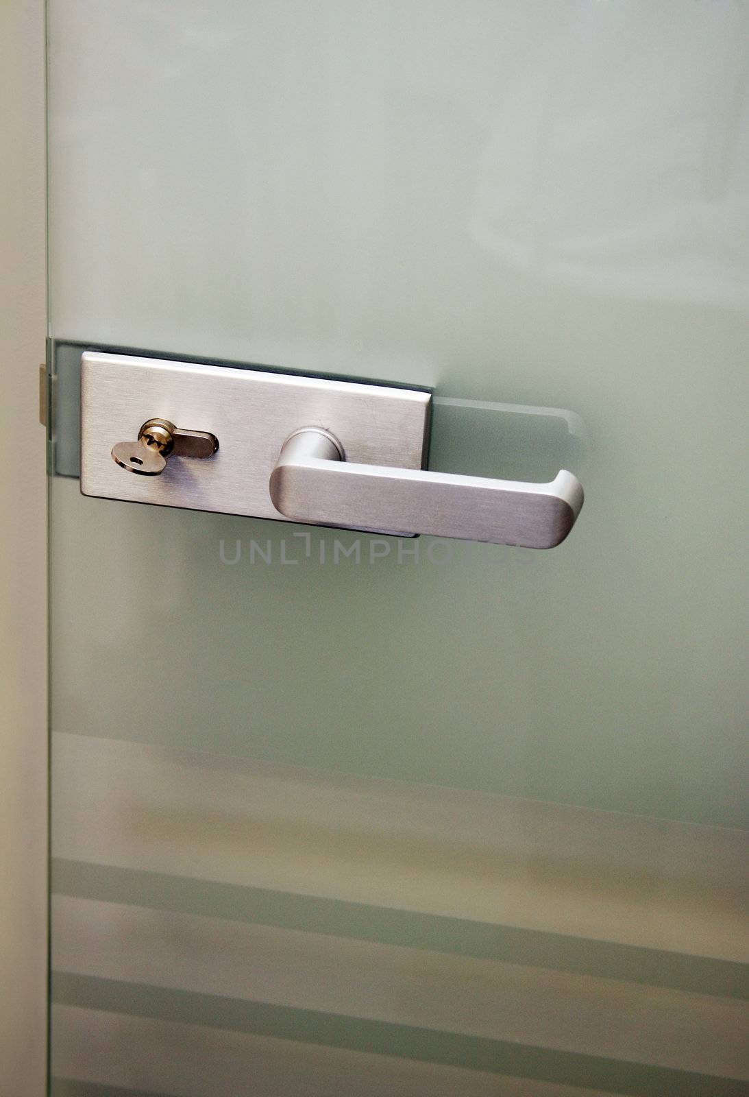 Metal door handle and the lock on a glass door