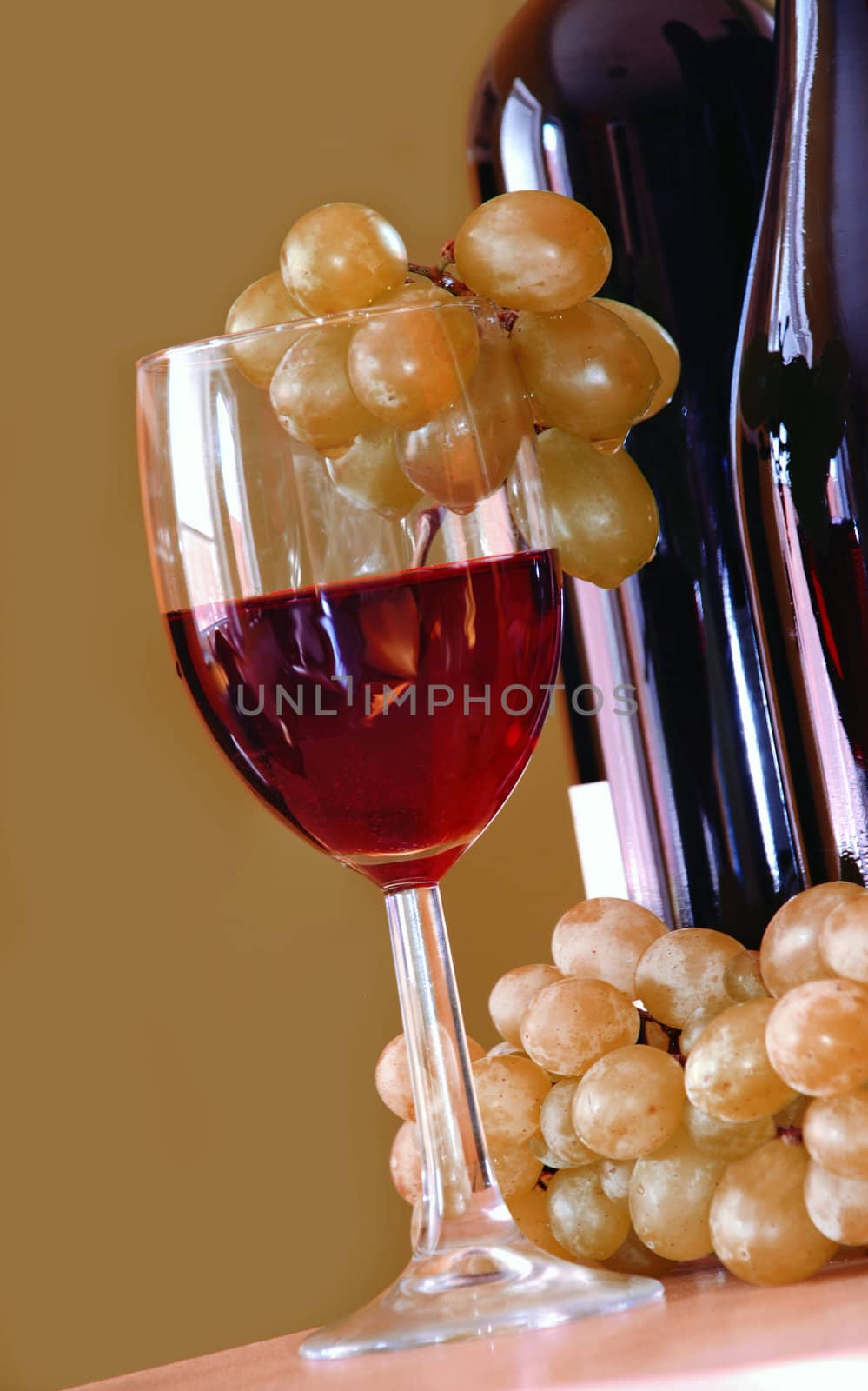 Red wine glass with grape and bottle over green