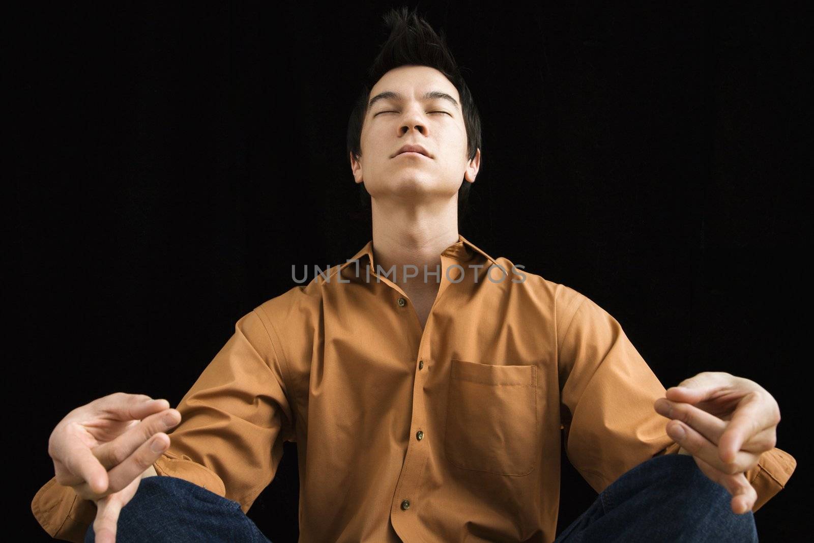 Asian young man sitting in meditative lotus position.