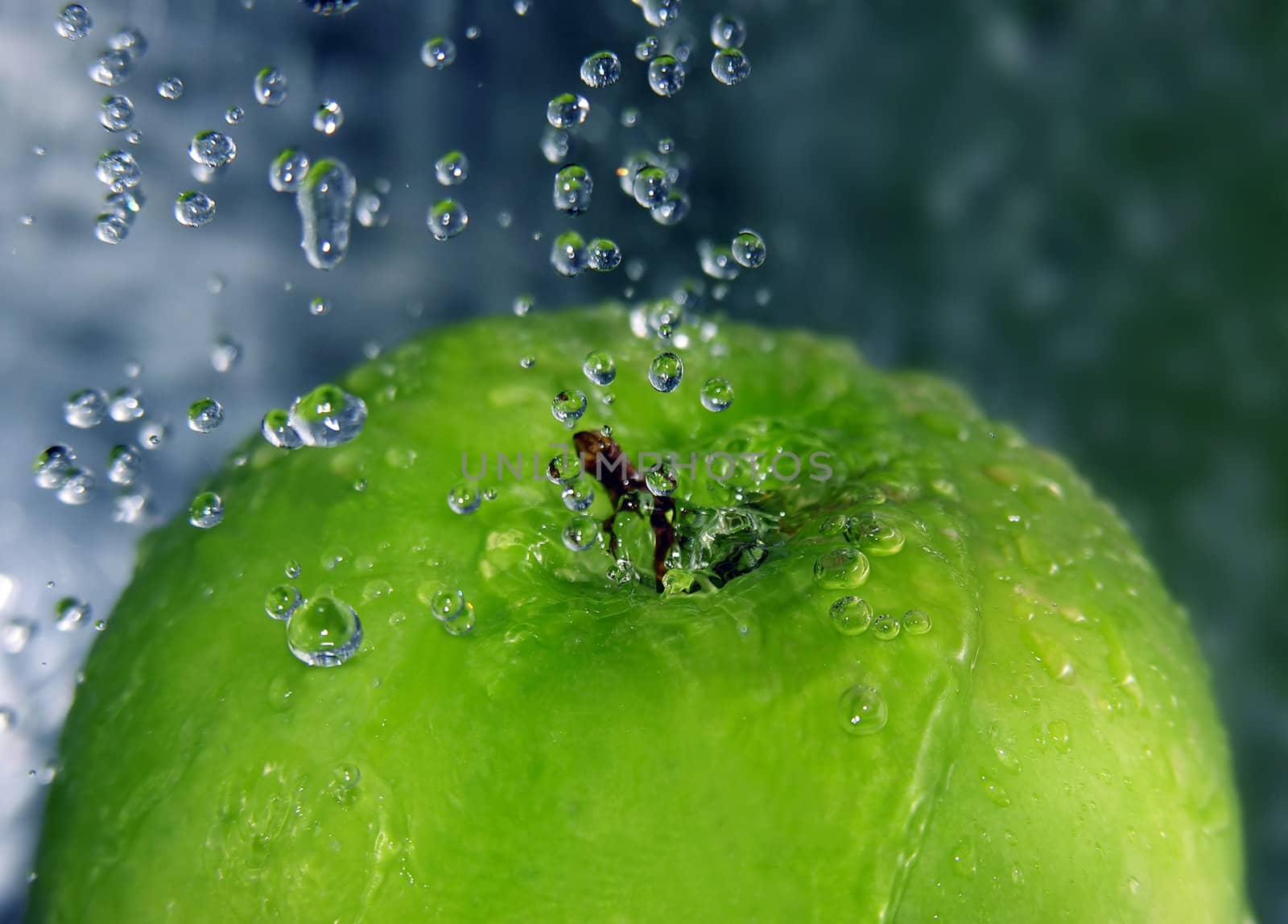 Water drops falling onto a green apple