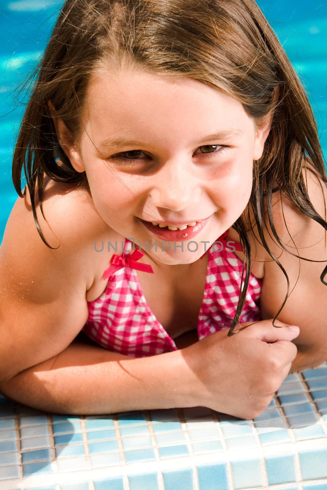 Young child enjoying the sun in and around the swimming pool