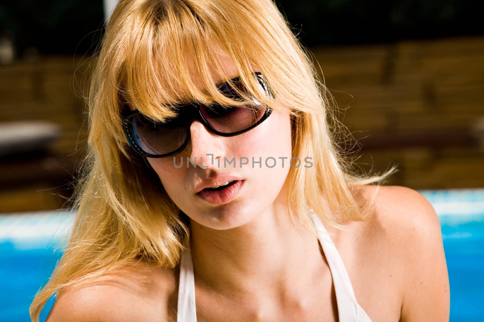 Young blond girl enjoying the sun in and around the swimming pool