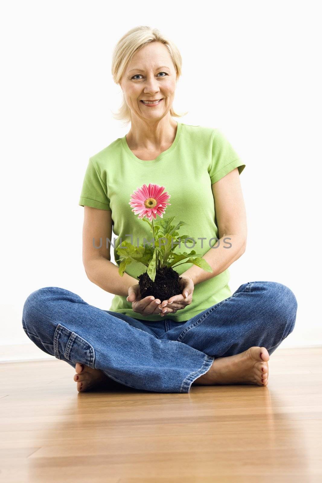 Smiling woman holding gerber daisy. by iofoto