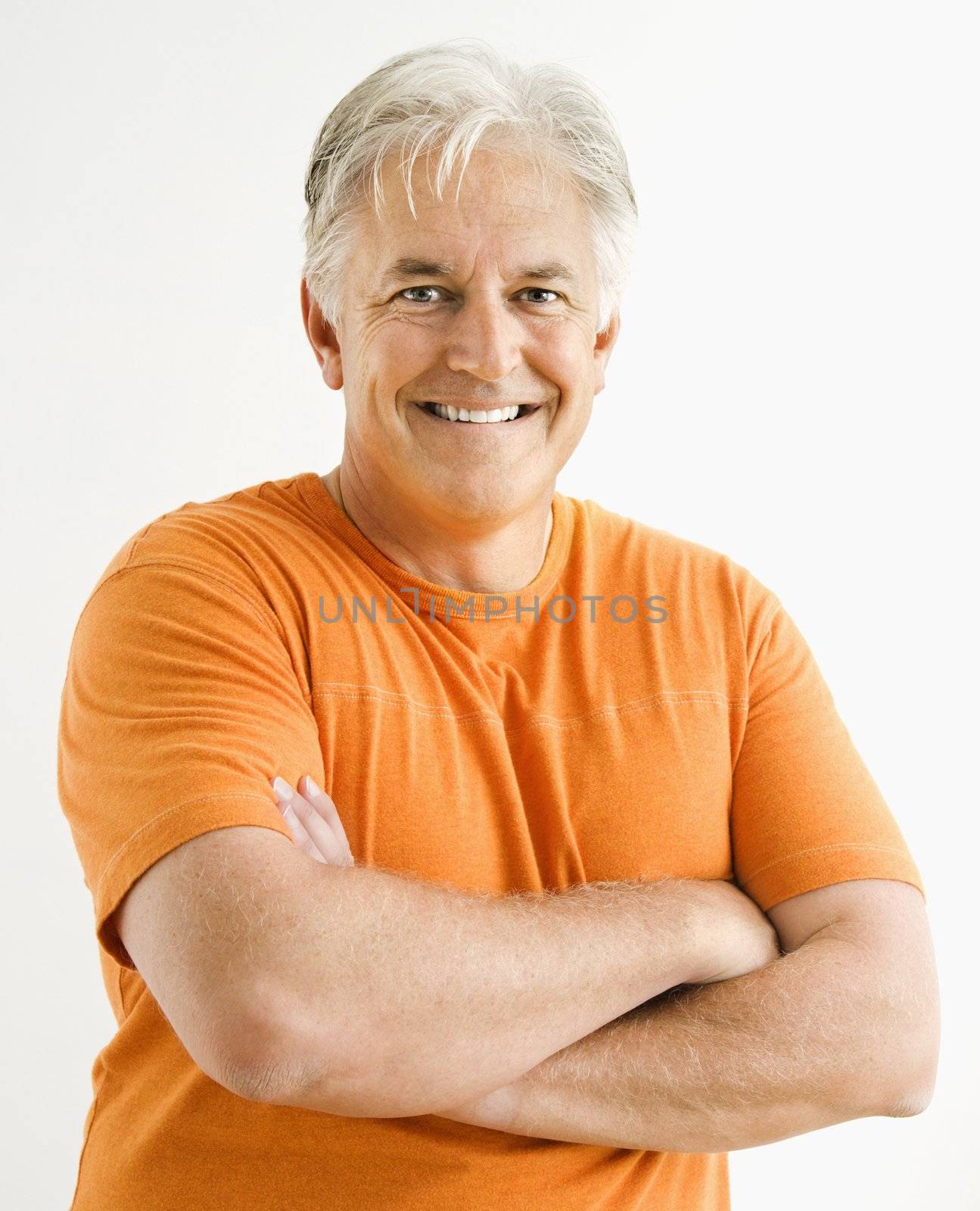 Portrait of smiling adult man standing looking at viewer with arms crossed.