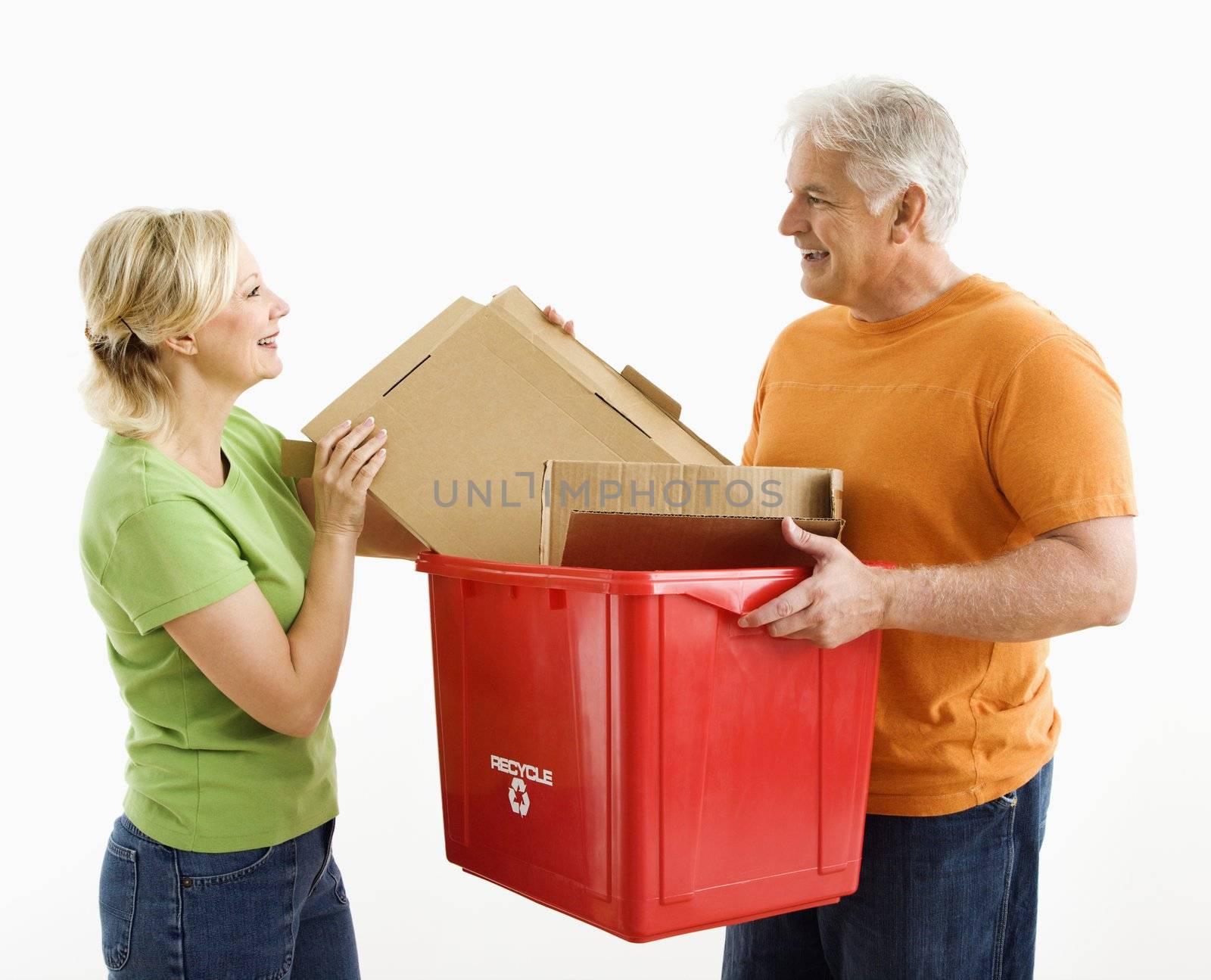 Man holding recycling bin while woman places cardboard into it.