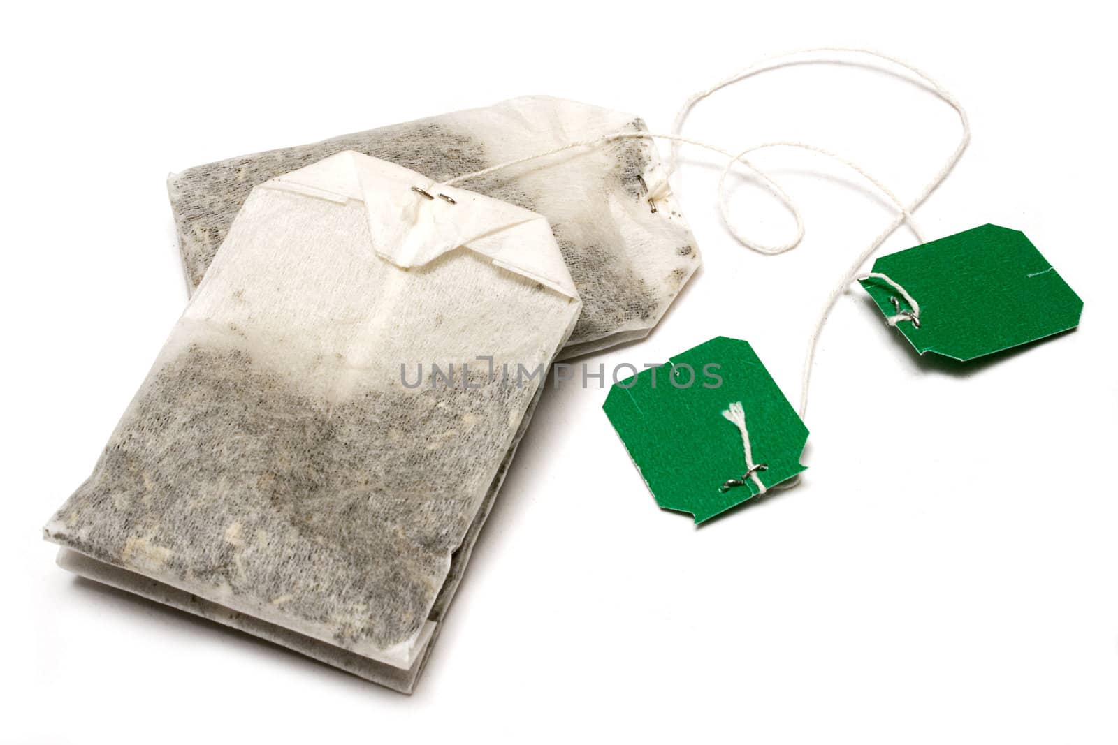 Two dry teabags with green tag isolated on a white background.