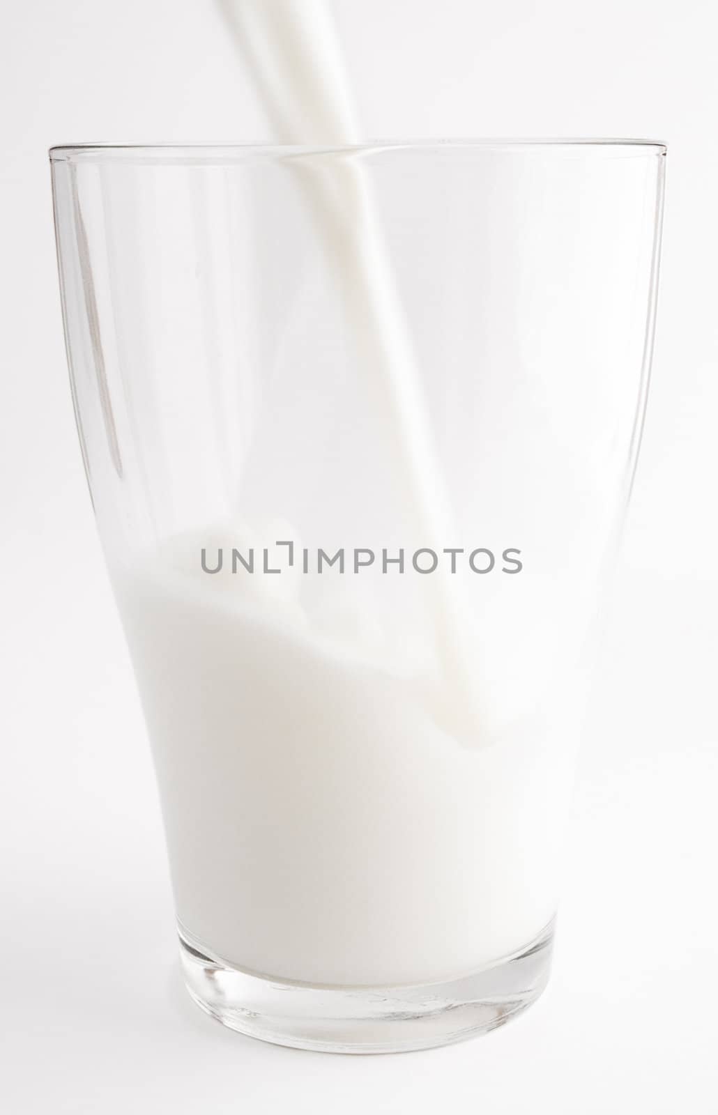 Pouring milk in a glass. White background.