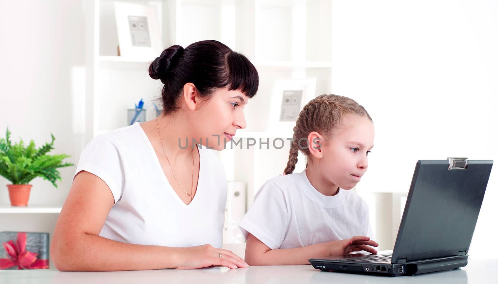 Mom and daughter are working together for a laptop at home