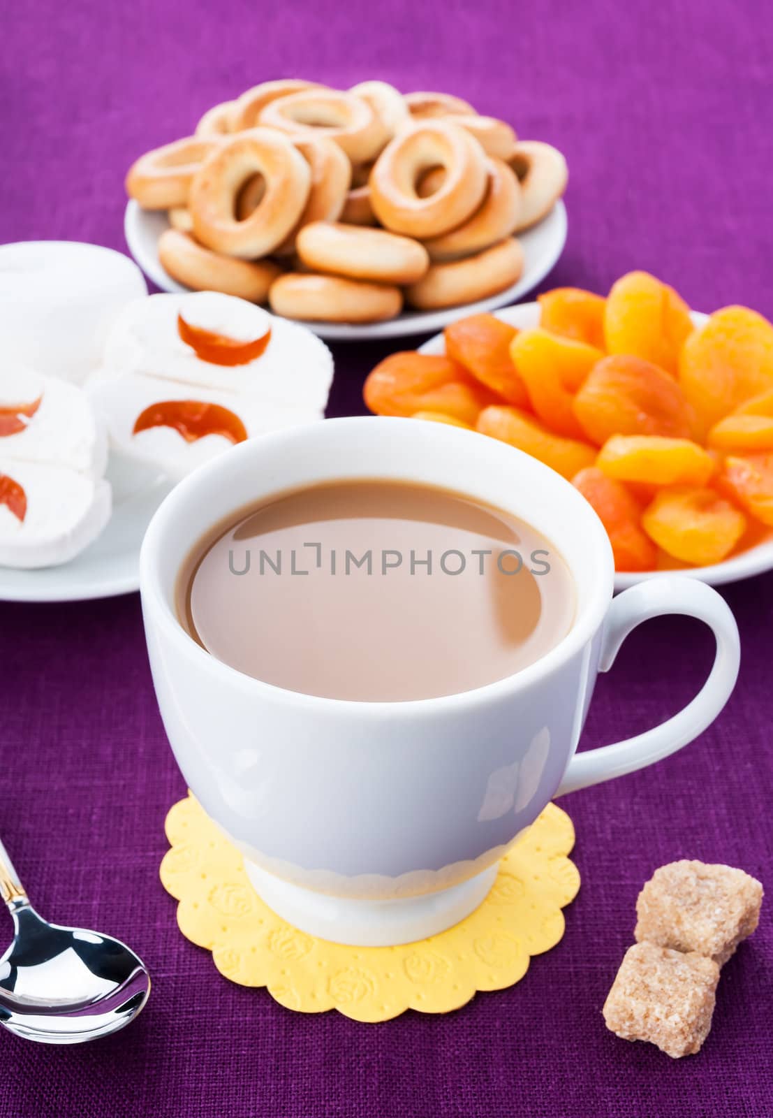 White cup of coffee with breakfast items on the lilac textured linen napkin