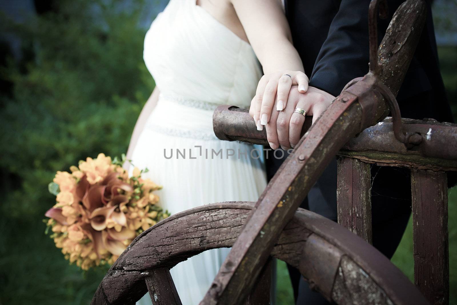 Young married couple holding hands - with wedding bouquet