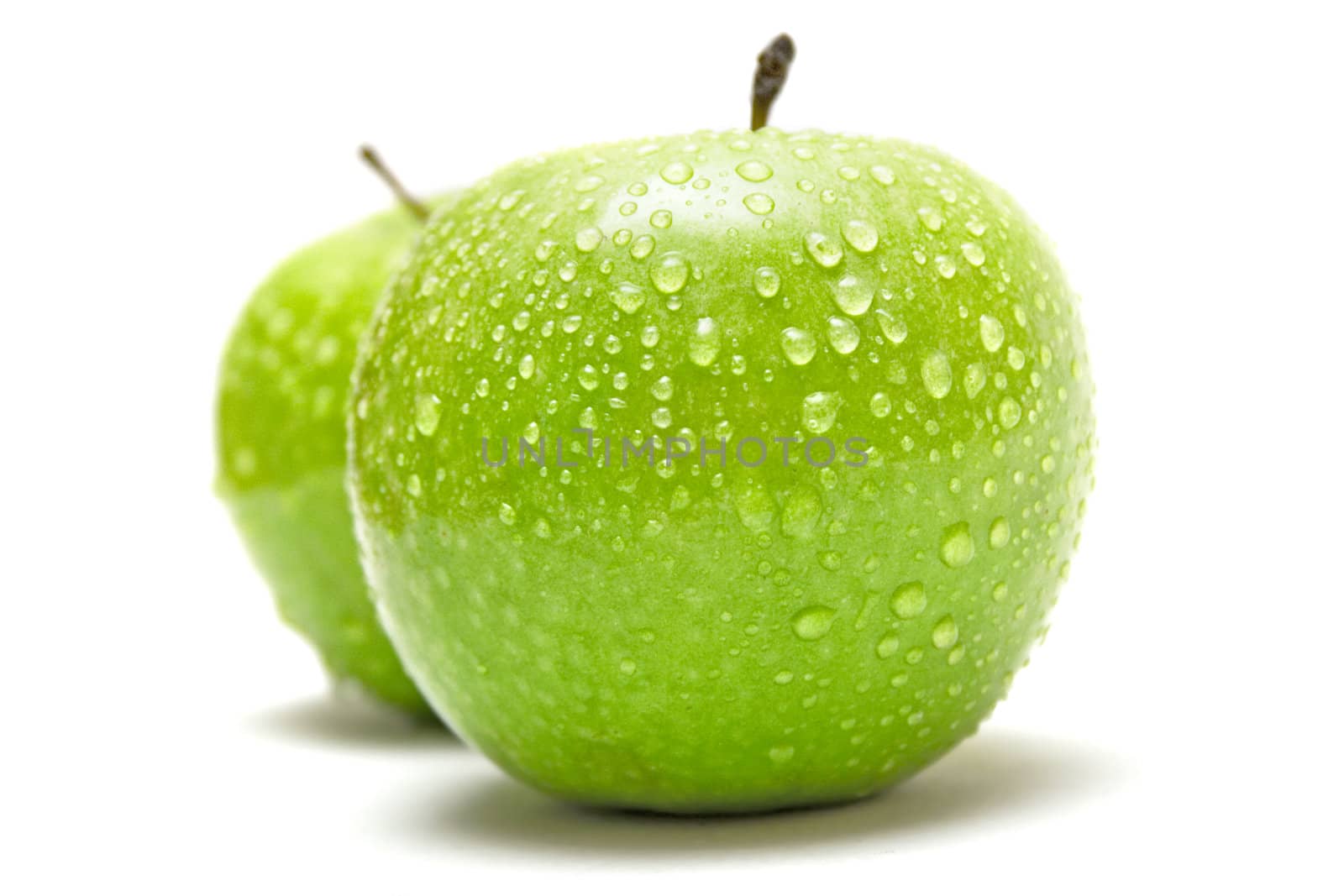 Two wet granny smith apples isolated on a white background.