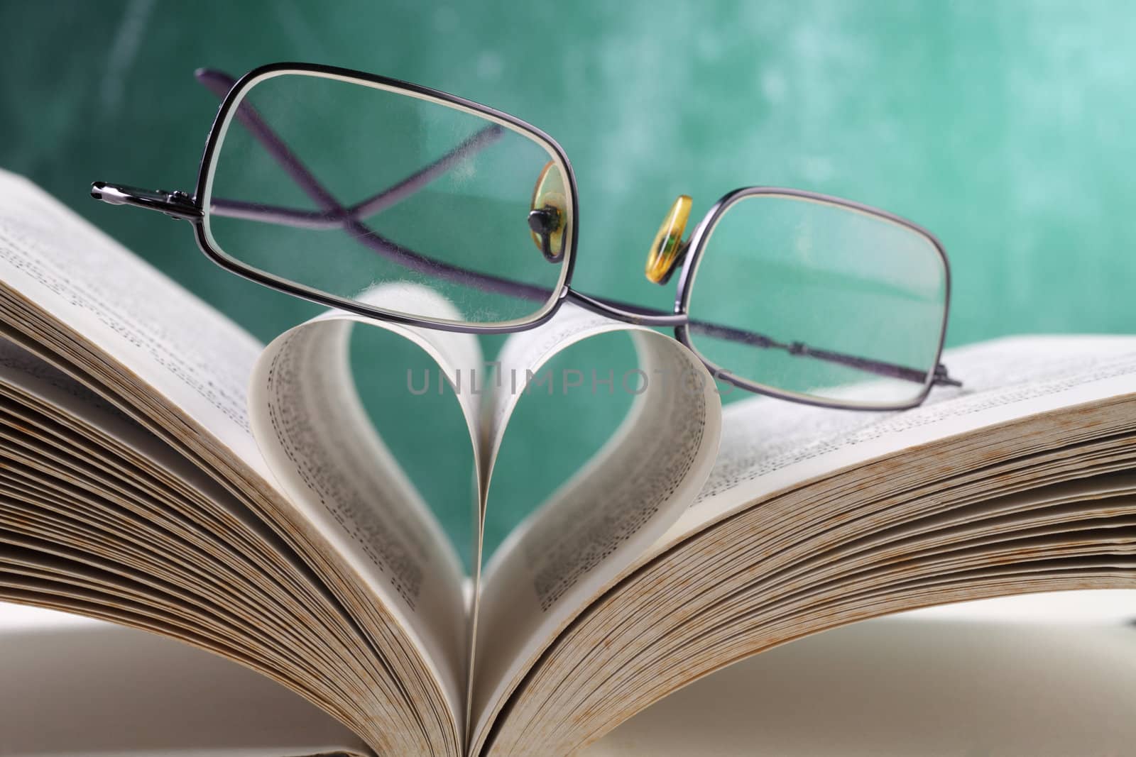 spectacels resting on book with heart shape