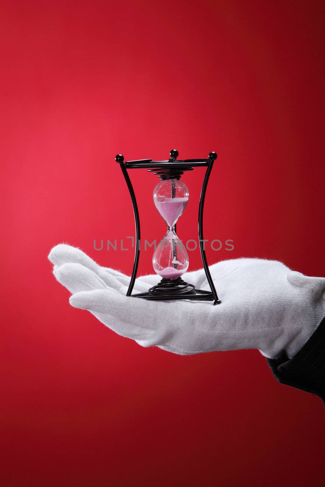 man with the white hand glove holding an hour glass