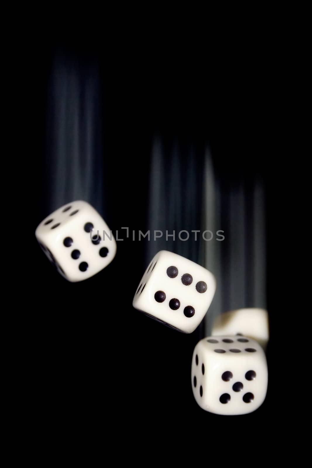 White dice falling. Motion blur. Black background.