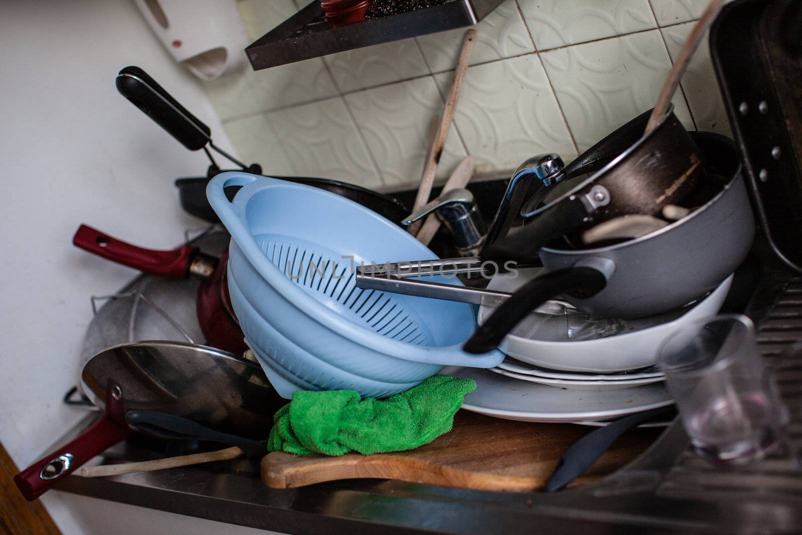 a lot of dirty pans, glasses and other kitchen utensils in a sink